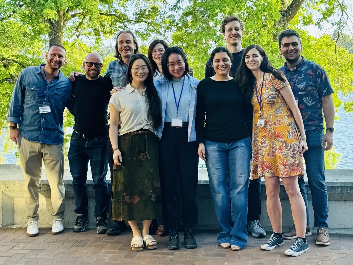 Attendees of the CoNECTome meeting gathered outdoors under trees by the water